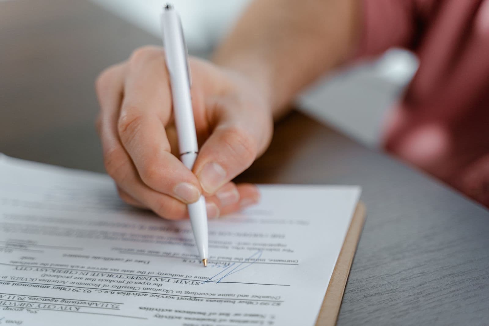 Close-up of a hand signing a legal document with a fountain pen