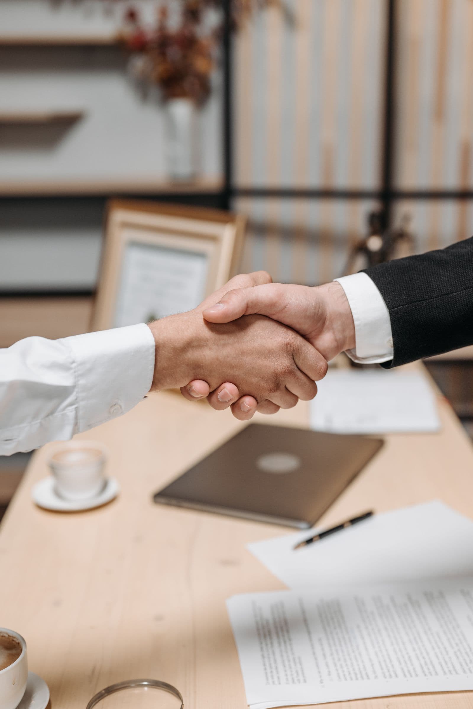 Attorney and client shaking hands across a desk after a successful meeting